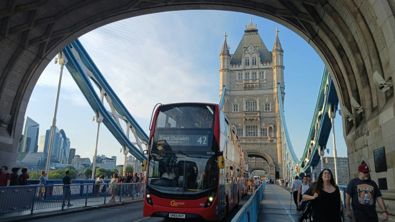 A red double decker bus driving over a bridge